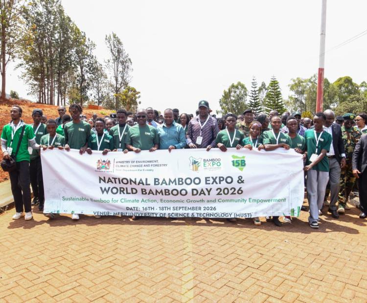Forest Development Secretary Mr. George Tarus walks alongside Meru University students while holding a World Bamboo Day Banner